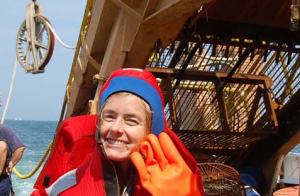 NOAA Teacher at Sea, Lisbeth Uribe, in her survival suit next to the dredge