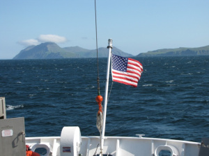 We sought a better anchorage southwest of Ukolnoi Is. when a 30 knot wind picked up. White caps cover the surface, the flag blows straight out facing aft.