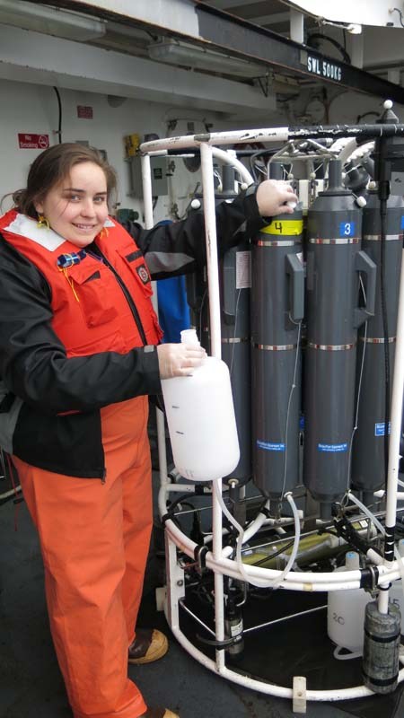 DJ Kast helping Jessica collect her 4 L of seawater from the Niskin bottle in the Rosette. Photo by Jerry P. 