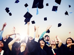 Graduates throwing mortar boards in the air