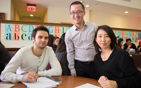 Adult students sit at tables with notebooks