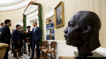 President Obama speaks with youth in the oval office with a bust of Martin Luther King Jr in the foreground