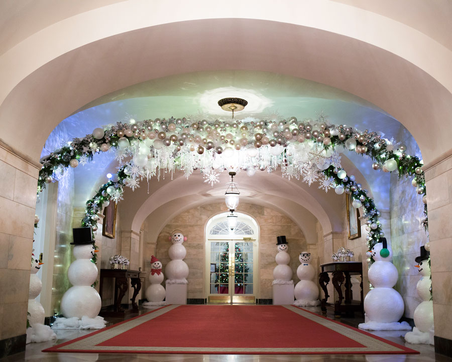 The East Colonnade is decorated with crystals hanging in the air like snowflakes, ribbons cascading from the ceiling, and rows of trees twinkling brilliantly just outside the windows.