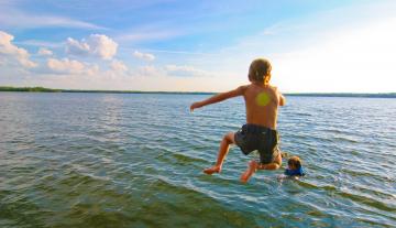 Boy jumping into lake