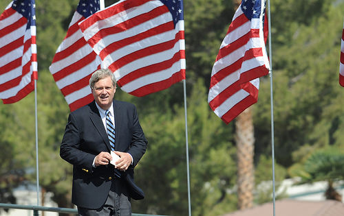 Agriculture Secretary Tom Vilsack behind a row of American flags