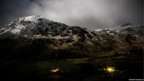 Night shot of snow covered mountains. Lights glimmer in the houses nearby