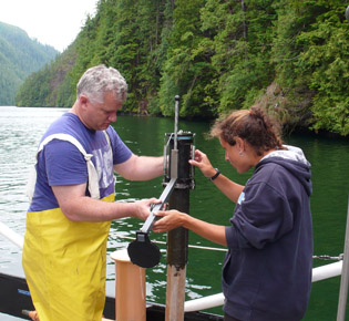 Two people on a boat, examining equipment