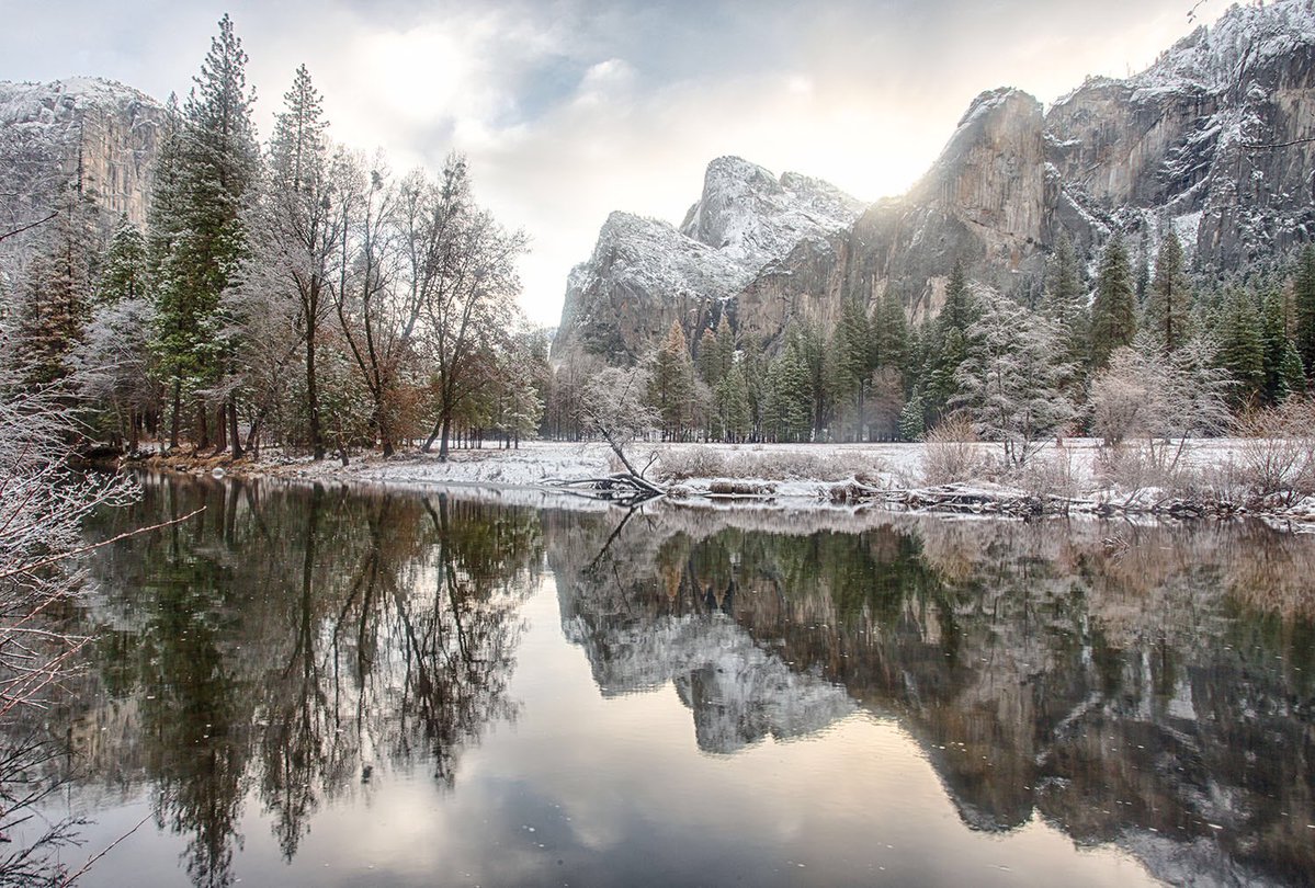 A dusting of snow covers trees and granite rock formations