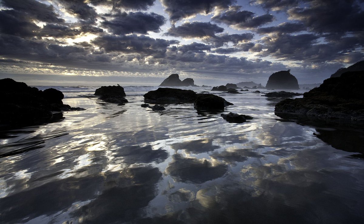 Clouds reflect in the water with sea stacks in the distance