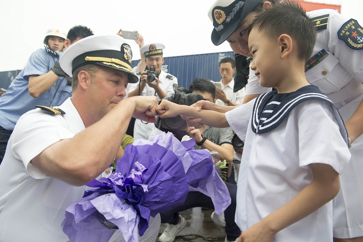 QINGDAO, China (Aug. 8, 2016) Cmdr. Justin Harts, commanding officer aboard the Arleigh Burke-class guided-missile destroyer USS Benfold (DDG 65), greets a child and receives a bouquet of flowers from members of the Peoples Liberation Army Navy. Benfold is currently underway in the 7th Fleet area of operations in support of security and stability in the Indo-Asian-Pacific. U.S. Navy photo by Mass Communication Specialist 3rd Class Deven Leigh Ellis/Released 