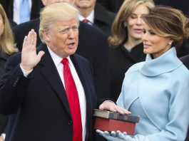 President Trump with one hand raised and one on bible being held by Melania Trump (© AP Images)