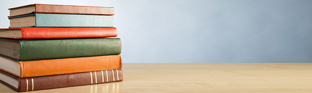 A pile of colorfully bound books on a desk