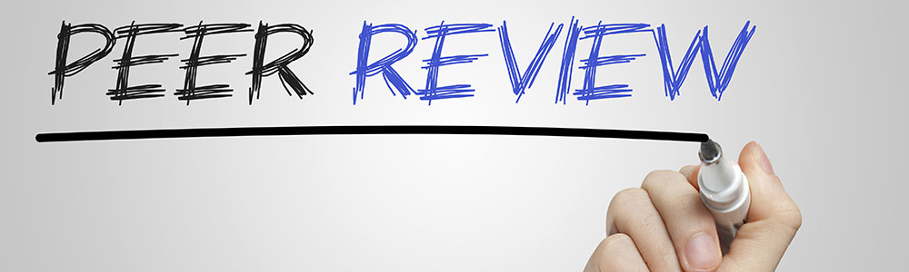A hand writing 'Peer Review' on glass