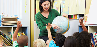 A teacher holding a globe and students with their hands raised