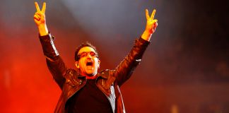Bono raising hands in peace signs (© AP Images)
