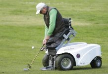Man without legs braced and positioned by machine for golfing (© AP Images)