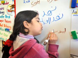Siswa-siswa AS, seperti gadis muda yang sedang menulis nama adiknya di papan tulis kelas ini, makin banyak yang belajar bahasa Arab. (© Getty Images/Portland Press Herald)
