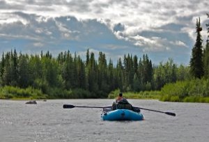 Rafter on the Gulkana Wild and Scenic River on a partly cloudy day