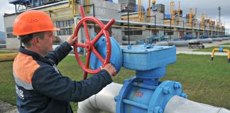 Man wearing hard hat turning valve on pipeline (© AP Images)