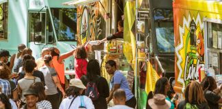 Crowd of people gathering around food trucks on the street (Shutterstock)