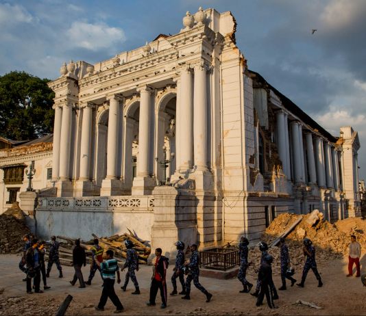 A white, columned building with people walking by (© AP Images)