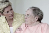 A photo of a younger woman comforting an elderly woman