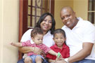 Family of four sitting in front of house.