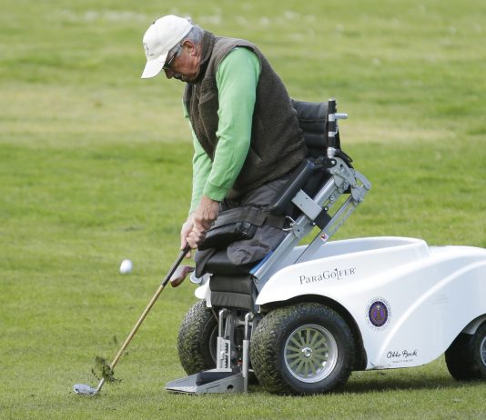 Hombre sin piernas que se sostiene y posiciona con una máquina para jugar al golf (© AP Images)