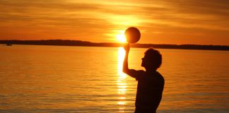 Silhouette of man standing near water in sunset (© Latif Abdul)