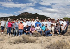 A group of about 40 people of various ages poses in a sagebrush landscape.