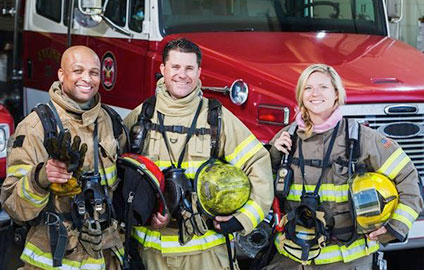 Photo of a group of diverse fire fighters in front of a fire truck