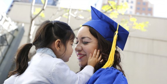 Smiling Mother in graduation gown holding Daughter