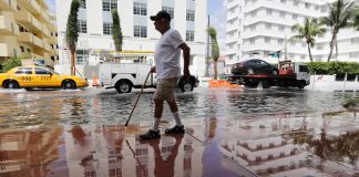 Homem anda por rua inundada (© AP Images)