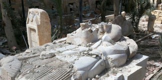 Une statue très endommagée au milieu de ruines (© AP Images)