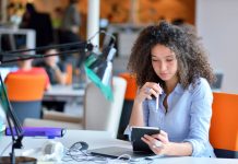 Wanita muda duduk di meja di kantor (Shutterstock)