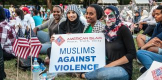 Quatro meninas sentadas no chão do National Mall seguram uma placa com os dizeres "muçulmanos contra a violência" (Depto. de Estado/D.A. Peterson)