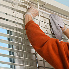 A person cleaning blinds
