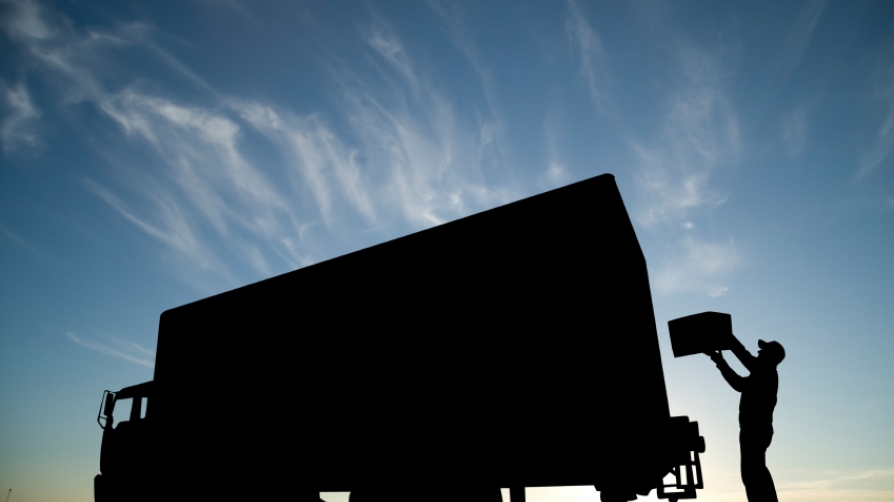 A man loading a box into a moving truck.