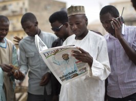 Warga Nigeria membaca koran di Kano, bagian utara Nigeria, pada hari kedua penghitungan suara pemilu 2015. (© AP Images)