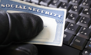 An identity thief holds a Social Security card in front of a keyboard