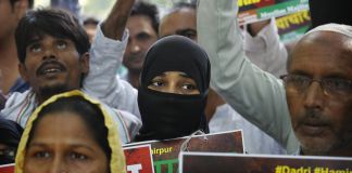 بھارتی احتجاجی کتبے اٹھائے کھڑے ہیں۔ (© AP Images)