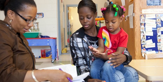 A Head Start teacher holds a meeting with a mother and her daughter.