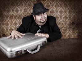 Man in black hat furtively touching silver metal briefcase (Shutterstock)