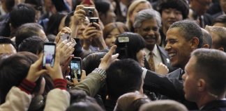 El presidente Obama sonríe rodeado de personas tomando fotos (© AP Images)