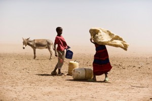 A boy and a woman struggle with the dusty wind looking for water in Wajir, Kenya