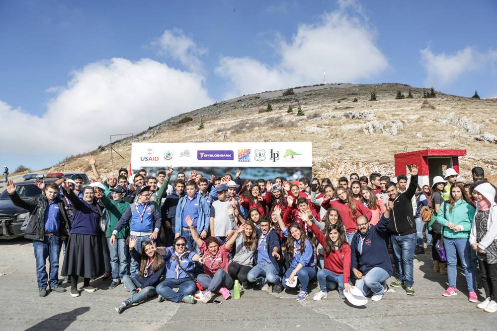 Large group of students waving in front of sign; mountain in background (Courtesy of the Lebanon Reforestation Initiative)