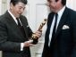President Ronald Reagan holds an Oscar statuette while Frank Hodsoll looks on