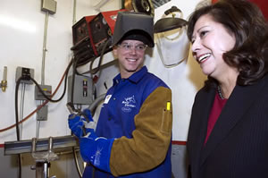 Secretary Solis with a service member using welding equipment