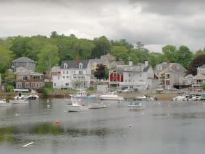 Recreational boats on quiet water with seaside homes in background.