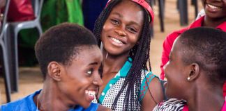 Des jeunes filles souriantes dans une salle de classe, l’une d’elles portant un bandeau « I love YTF » dans les cheveux (Photo offerte par Youth for Technology Foundation)